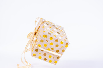 Closeup gold gift box with a gold bow on white background. The gift flies in the air. Boxing day or birthday concept.