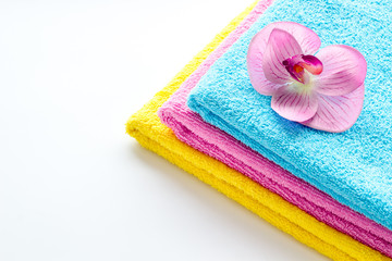 Obraz na płótnie Canvas Clean towels - stack of laundred linen with orchid flower - on white background copy space