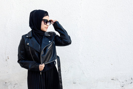 Portrait of beautiful middle-eastern girl in traditional Islamic clothing - hijab. Modern and young Iranian woman in sunglasses and a leather jacket