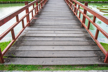 Obraz premium Small wooden bridge cross over the pond in garden park.