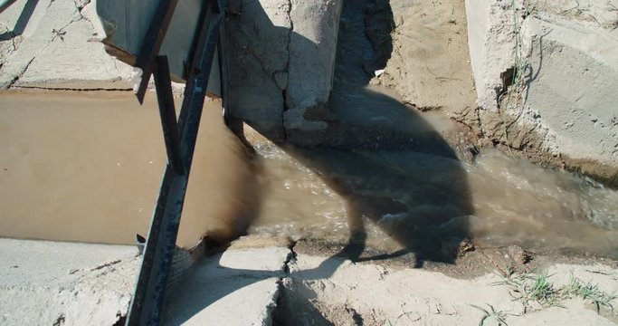 Vertical gate on cement irrigation ditch showing water flow