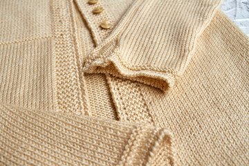 Fototapeta na wymiar Sleeves on a beige knitted sweater. Closeup, selective focus