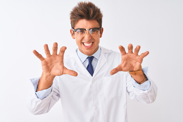 Young handsome sciencist man wearing glasses and coat over isolated white background smiling funny doing claw gesture as cat, aggressive and sexy expression