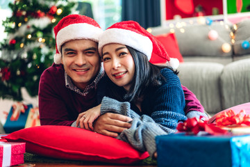 Romantic sweet couple in santa hats having fun and smiling while celebrating new year eve and...