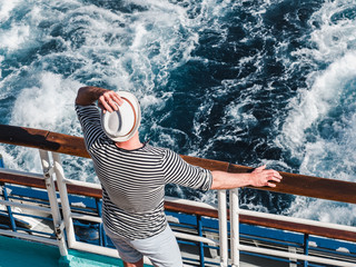 Smiling man on the empty deck of a cruise liner on the background of sea waves. Top view, close-up....