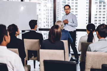 Businessman standing in front of group of people in consulting meeting conference seminar at hall...