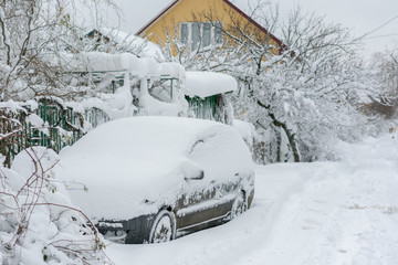 Snow-covered machine. Car under the snow. Lots of snow and big snowdrifts on the street. Vehicles...