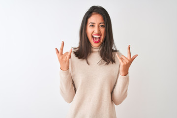 Beautiful chinese woman wearing turtleneck sweater standing over isolated white background shouting with crazy expression doing rock symbol with hands up. Music star. Heavy music concept.