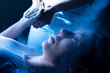 Fototapeta na wymiar Beauty treatment of face with ozone facial steamer in beauty center. Blue backlight.