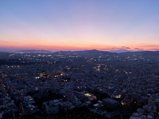 Obraz premium Panorama miasta o zachodzie słońca. Krajobraz zmierzchu z miastem, górami i chmurami w promieniach zachodzącego słońca. Ateny, Grecja