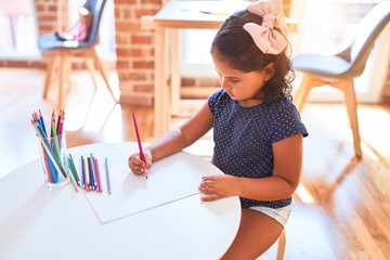 Beautiful toddler girl drawing cute draw using colored pencils at kindergarten
