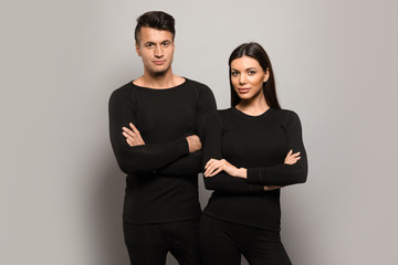 Couple wearing thermal underwear on grey background