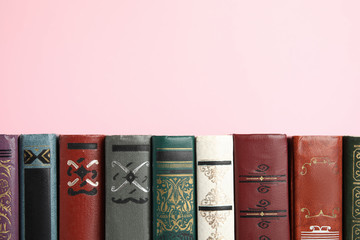 Collection of old books on pink background, space for text