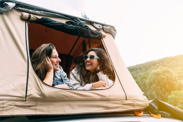 Two women talking in their tent while camping in the wild