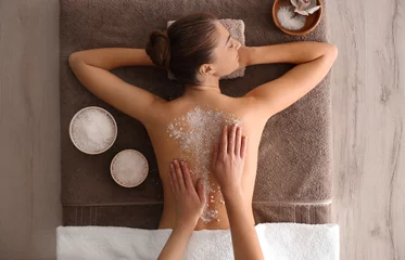Poster Young woman having body scrubbing procedure with sea salt in spa salon, top view © New Africa