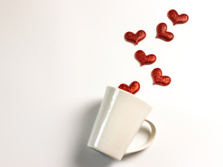 Flat layout of red glitter hearts  moving out from white mug on white background,