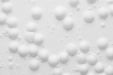Soft light white fluid paint background with many large round bubbles as abstract texture.