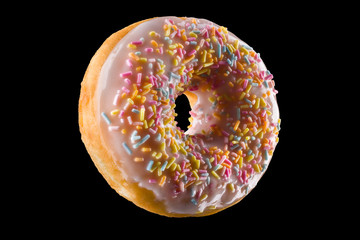 Glazed donut with sprinkles on a black background rotated in three quarters