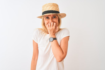 Middle age woman wearing casual t-shirt and hat standing over isolated white background looking stressed and nervous with hands on mouth biting nails. Anxiety problem.