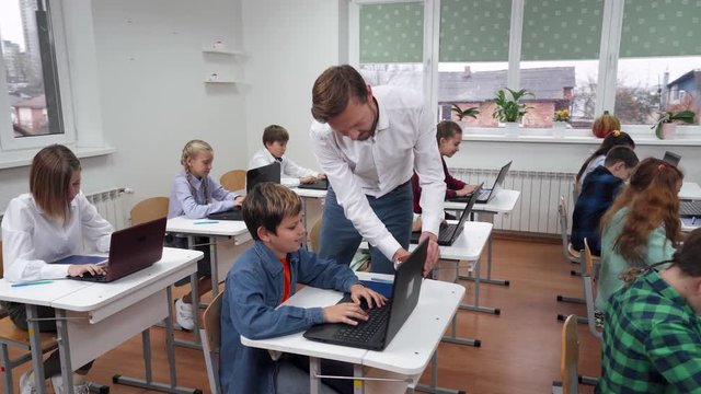 Education in the modern school, children use laptops, teacher monitors the implementation of the test work, the learning process at school.