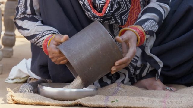 Indian woman transferring the powdered bajra / millet into the plate . Free video for commercial use - A woman preparing bajra atta for an evening meal in a village home in India