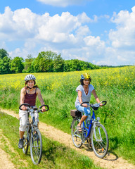 Fototapeta premium Zwei Frauen mit dem Fahrrad unterwegs auf dem Land