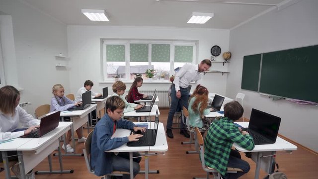 Education in the modern school, children use laptops, teacher monitors the implementation of the test work, the learning process at school.