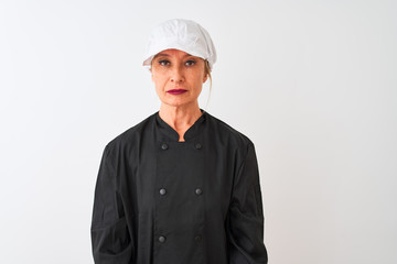 Middle age chef woman wearing uniform and cap standing over isolated white background with serious expression on face. Simple and natural looking at the camera.