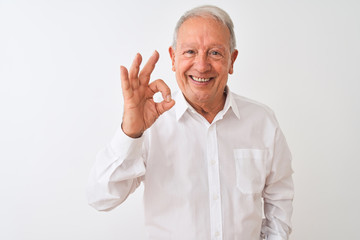 Senior grey-haired man wearing elegant shirt standing over isolated white background smiling positive doing ok sign with hand and fingers. Successful expression.