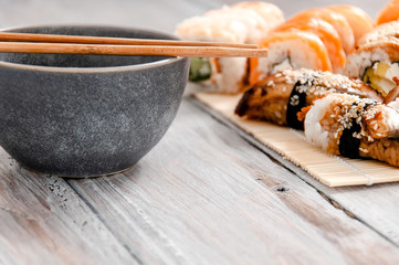 Sushi and soy sauce in a bowl and wooden chopsticks on a gray wooden table. Japanese food. Sushi Set. Variety of rolls. Menu.