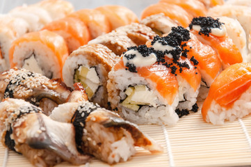 Sushi and soy sauce in a bowl and wooden chopsticks on a gray wooden table. Japanese food. Sushi Set. Variety of rolls. Menu.