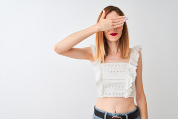 Naklejka premium Beautiful redhead woman wearing casual t-shirt standing over isolated white background smiling and laughing with hand on face covering eyes for surprise. Blind concept.