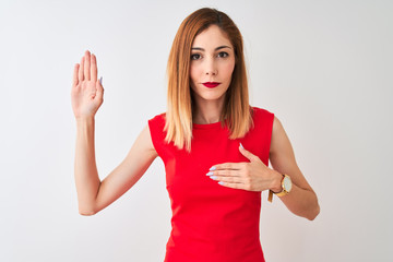 Fototapeta premium Redhead businesswoman wearing elegant red dress standing over isolated white background Swearing with hand on chest and open palm, making a loyalty promise oath