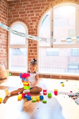 Young beautiful blonde girl kid enjoying play school with toys at kindergarten, smiling happy playing with building blocks at home