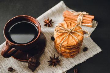 Homemade cookies and brown cup with coffee on dark background