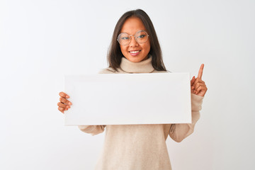 Fototapeta premium Young beautiful chinese woman wearing glasses holding banner over isolated white background surprised with an idea or question pointing finger with happy face, number one
