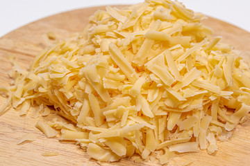 Cheese grated on a round cutting Board on a white background