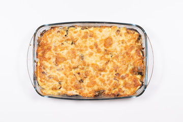 Baked salmon with potatoes under a cheese brown crust in a glass pan on a white background