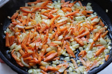 frying onions with carrots in a frying pan