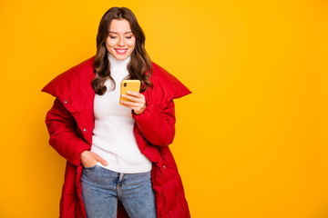 Photo of charming pretty lady holding telephone hands checking followers subscribers wear red winter outerwear overcoat isolated yellow color background