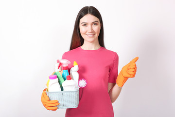 A young housewife holds in his hands cleaning products on a colored background.