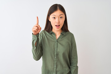Young chinese woman wearing casual green shirt standing over isolated white background pointing finger up with successful idea. Exited and happy. Number one.