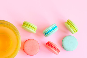 a Cup of green tea and colorful macaroons on a pink background