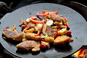 The chicken and various vegetables are grilled by the campfire