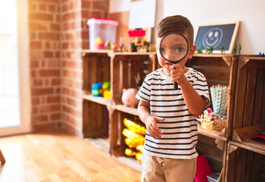Beautiful toddler boy using magnifying glass at kindergarten - Powered by Adobe