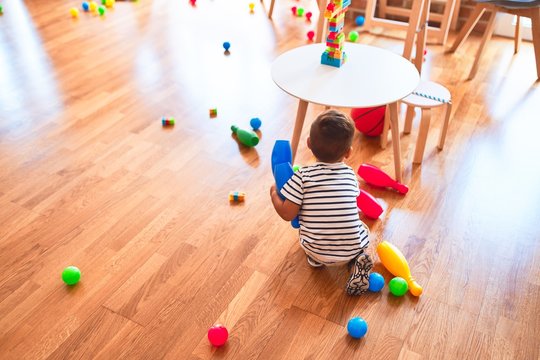 Beautiful toddler boy playing bowling at kindergarten
