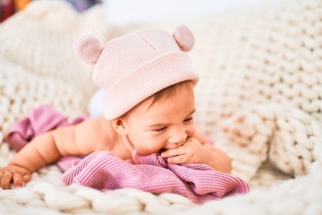 Adorable baby lying down over blanket on the sofa at home. Newborn wearing fanny hat relaxing and resting comfortable