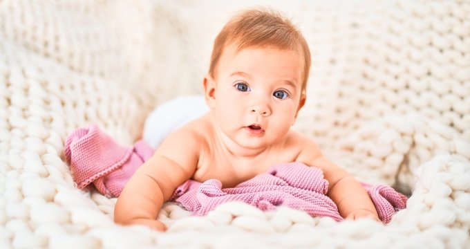 Adorable baby lying down over blanket on the sofa at home. Newborn relaxing and resting comfortable