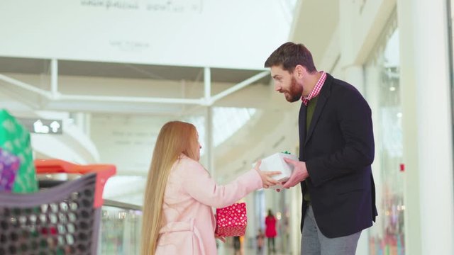 Father and his daughter exchanging Christmas present boxes gifts on shopping center talk dad child shop customer love walking winter xmas close up slow motion
