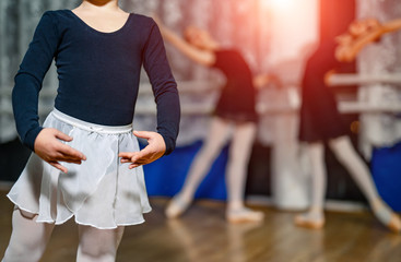 Cute little ballerina in dance studio posing and training with ballet team in the background....